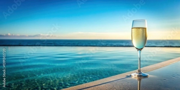 Fototapeta A sparkling wine glass is placed on the edge of a pool overlooking a serene ocean landscape with gentle waves and a clear blue sky above , ocean view, water features