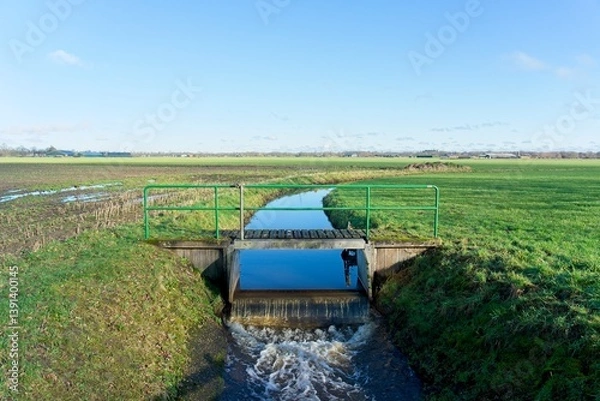 Fototapeta Sluice dewatering water from the farm fields of the Gelderse Vallei between the hills of the Veluwe in Gelderland and the Utrechtse Heuvelrug in Utrecht in the Netherlands