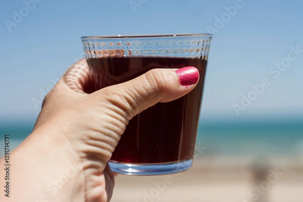 Obraz cropped shot of woman holding glass of red wine beach background. Horizontal. Copy space
