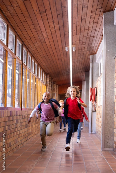 Obraz Running in school hallway, diverse children with backpacks enjoying recess time, copy space
