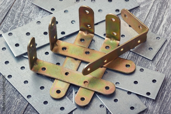 Fototapeta Collection of metal brackets and perforated metal plates for construction and woodworking for structural support. L-brackets and flat plates connection equipment.