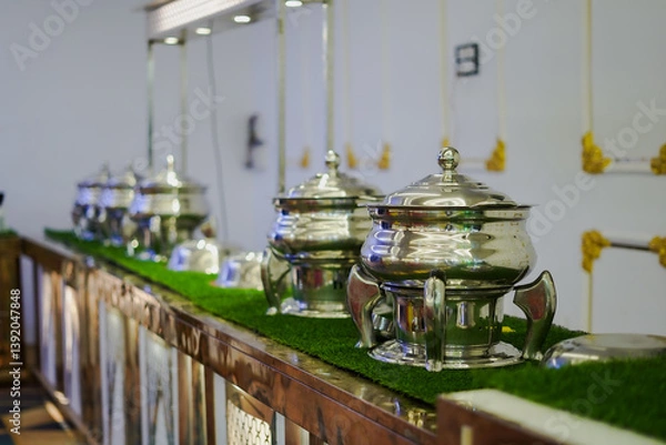 Fototapeta A buffet setup with shiny steel food warmers arranged on a decorated counter at a wedding or event.