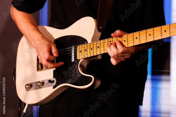 Fototapeta Hands skillfully play an electric guitar, focusing on finger movements and strings. The musician captures a moment of intense concentration and musical expression.