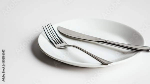 Fototapeta Empty white plate with fork and knife on white background, ready for meal, tableware