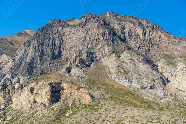 Obraz Dramatic mountain peak with rugged cliffs and rocky terrain, showcasing the raw beauty of barren landscape under clear blue sky. Kabardino-Balkaria, Chegemsky district