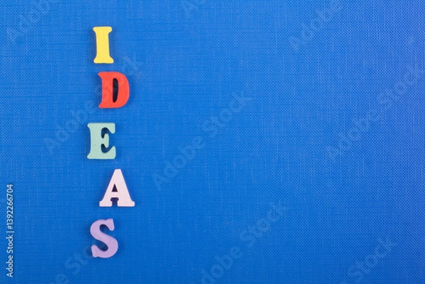 Obraz IDEAS word on blue background composed from colorful abc alphabet block wooden letters, copy space for ad text. Learning english concept.