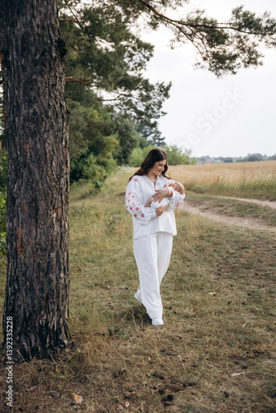 Obraz Mother in white dress with 1 month old son in her arms outdoors in a wheat field