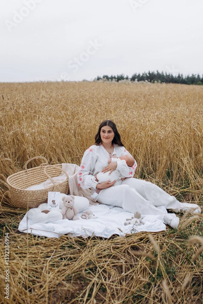 Obraz Mother in white dress with 1 month old son in her arms outdoors in a wheat field