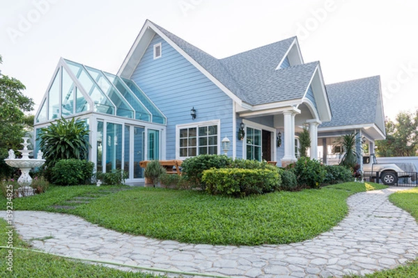 Fototapeta Bright blue house in sunlght with colorful poppies and some graceful trees.
