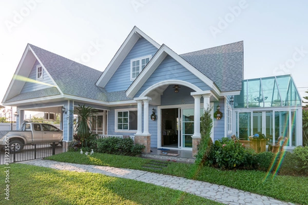 Fototapeta Bright blue house in sunlght with colorful poppies and some graceful trees.