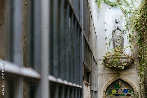Fototapeta Historic statue surrounded by ivy abandoned courtyard urban exploration overgrown environment wide angle artistic preservation