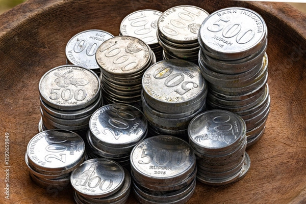 Fototapeta Stacks of Indonesian Rupiah Coins in a Wooden Bowl. Close-Up of 500, 1000, and 200 Rupiah Coins