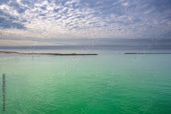 Fototapeta A quiet moment on the coast, a white sandy beach with emerald-green waters of Destin Harbor, with a lifeguard stand standing watch beneath the open sky, ready for sunny days and salty breezes.