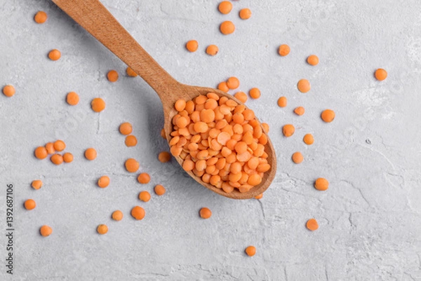 Fototapeta Organic red lentil on wooden spoon, close up texture, legumes for vegan and vegetarian cooking, pulses for healthy balanced diet, plant-based protein source