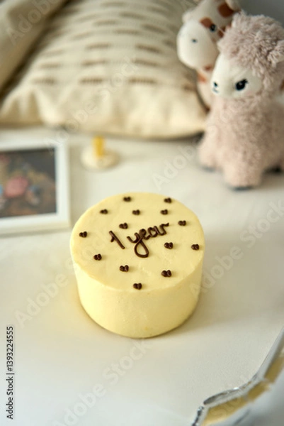 Obraz Adorable minimalist birthday setup with a "1 year" cake, soft toys, and cozy decor. Perfect for celebrating a baby’s first milestone in a warm and tender setting.