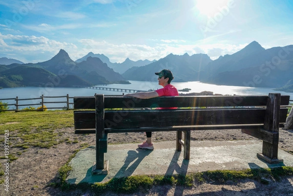 Fototapeta woman smiling by the bench contemplating the lake and the mountains of Riaño