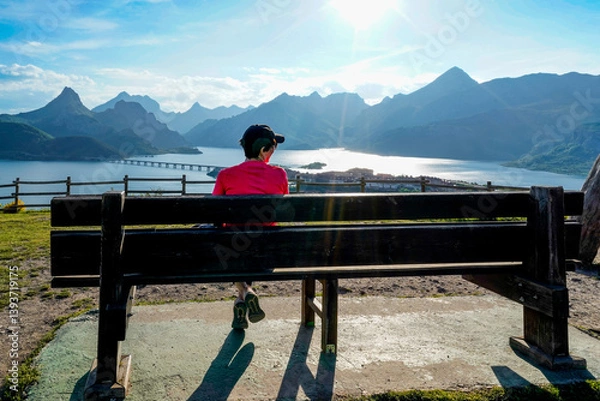 Fototapeta woman smiling by the bench contemplating the lake and the mountains of Riaño