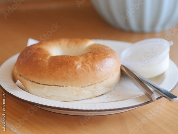 Fototapeta Bagel with cream cheese. Classic Baked Bagel bread serving on the plate. Famous quick and easy flour breakfast menu in restaurant.