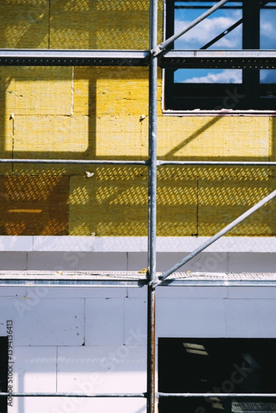 Obraz Mineral wool house insulation. Construction site with scaffolding and high-density slab insulation product installation on building facade.