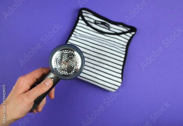 Fototapeta A woman's hand is about to clean lint from clothes.