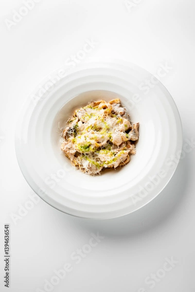 Obraz A luxurious bowl of fettuccine pasta topped with creamy sauce, grilled chicken, and a sprinkle of Parmesan cheese. The dish is garnished with fresh herbs, creating an enticing presentation.