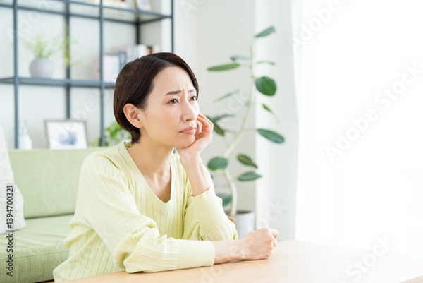 Fototapeta リビングで悩むミドルの女性