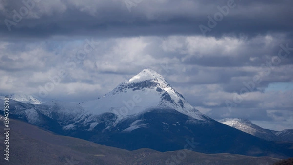 Fototapeta Imposing mountain peak covered with snow on a cloudy day