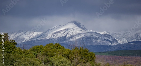 Fototapeta Imposing mountain peak covered with snow on a cloudy day