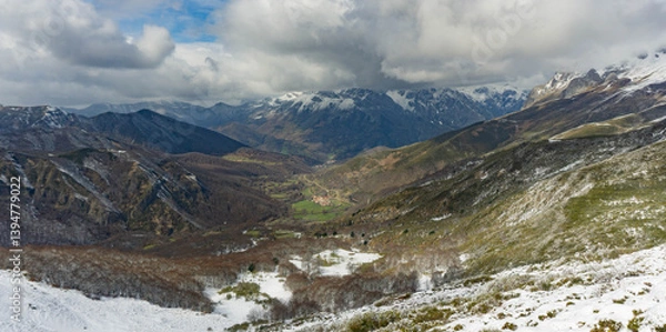 Fototapeta Mountain landscape of a valley on a cloudy day with a village in the depths of it