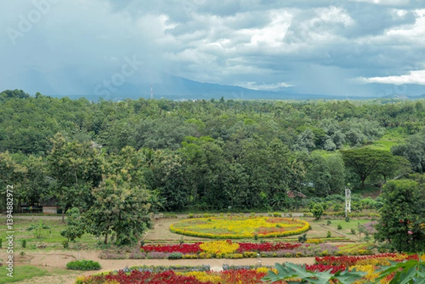 Obraz Colorful flower garden with lush greenery and mountain backdrop. High-angle view of a vibrant flower garden with various colorful flowers arranged in intricate patterns.