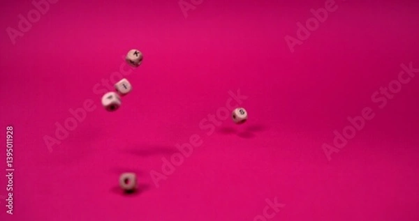 Fototapeta Brown beads in the shape of a square with letters written on them falling on a pink background, in slow motion