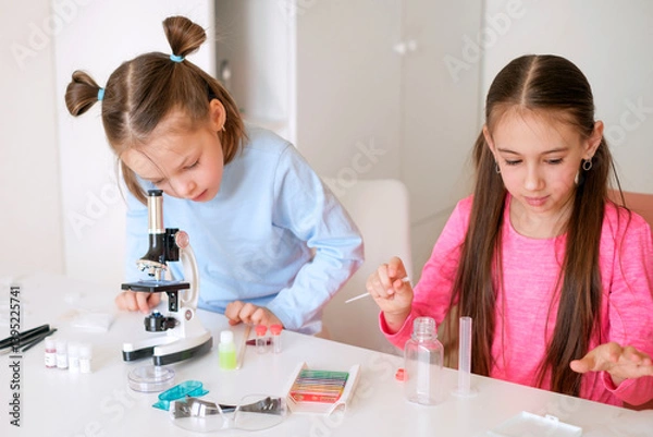 Obraz A girl stares intently into a microscope, examining the cells of organisms and objects in a biology lesson