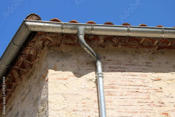 Fototapeta Gouttière zinc gris sur la façade de la maison, descentes rondes sur la façade en pierre