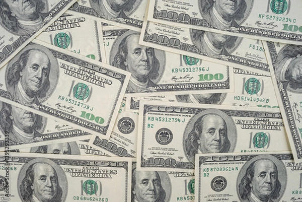 Fototapeta Scattered US hundred dollar bills with Benjamin Franklin portrait. Flat lay composition of American banknotes for finance and investment concept.