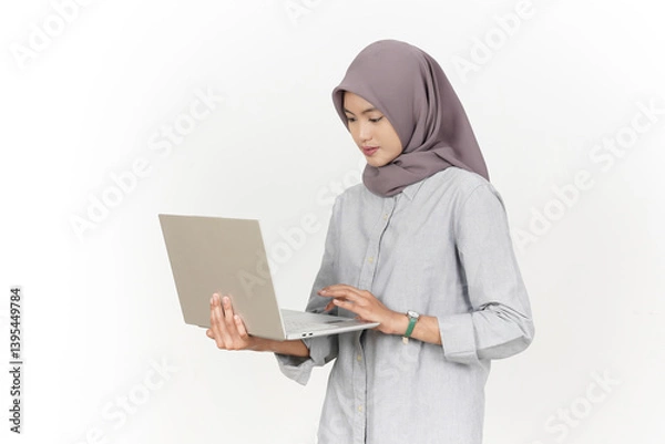 Obraz Holding and Using Laptop Of Beautiful Asian Woman Wearing Hijab Isolated On White Background