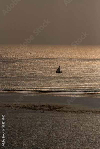 Fototapeta samotny, mały jacht żaglowy płynący wzdłuż rafy koralowej otaczającej lagunę, na tle wschodzącego słońca nad oceanem indyjskim, Kenia, Afryka