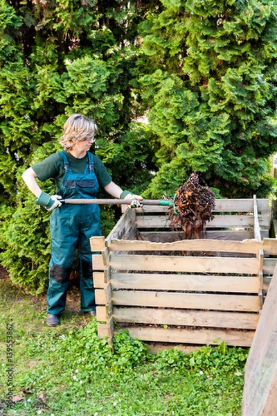 Obraz Young caucasian female tumbling the compost with a pitch fork