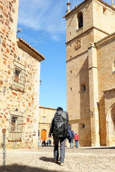 Obraz Pilgrims on the Camino de Santiago crossing the historic center of Cáceres, Extremadura, Spain. Pilgrims walking in front of the Cáceres Cathedral on the Via de la Plata.