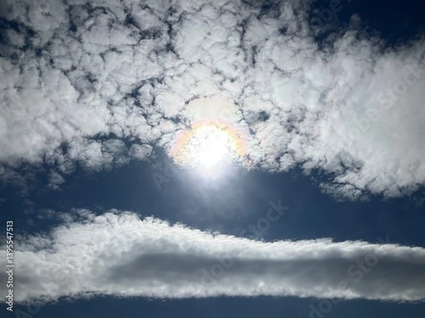 Obraz Blue sunny sky with Stratocumulus volutus, Roll clouds and pearl colors, optical phenomenon Iridescence on Altocumulus around sun. Topics: weather, meteorology, nature, airspace