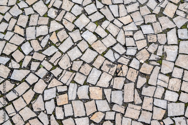 Fototapeta Fragment of a flat stone paved area, with earth and moss between the stones, to be used as an abstract background and texture.