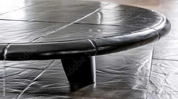 Obraz Round dark table stands indoors, textured flooring visible beneath
