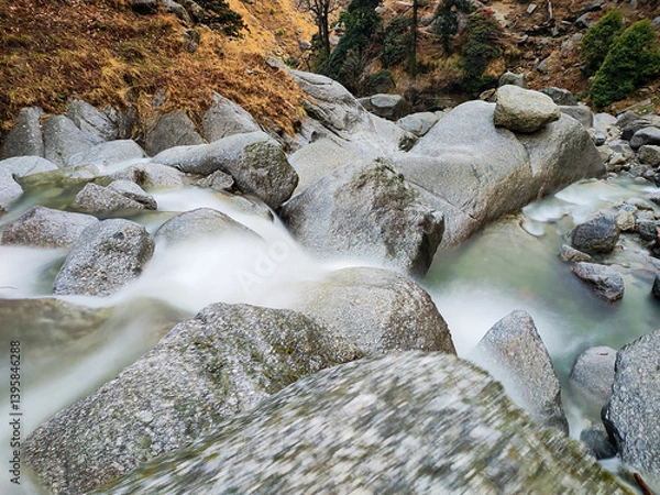 Fototapeta A long exposure nature scene, with beautiful silky waterfalls dropping into an emerald green pool, surrounded by blooming Rhododendron trees and rocks.