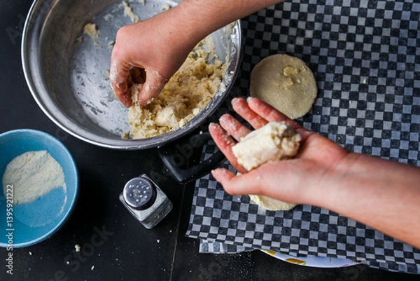 Obraz Close-up image showcasing hands taking arepa (colombian food) dough from pot with utensils, portraying culinary preparation.