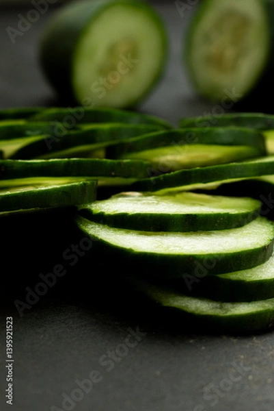 Obraz Close-up of sliced fresh cucumbers arranged on a dark background highlighting their texture and freshness, copy space.