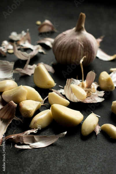 Obraz Vertical shot of A rustic scene featuring garlic cloves and peelings scattered, great for illustrating cuisine, food preparation, cooking concepts, and rustic or organic kitchen themes.