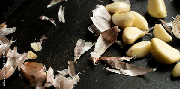 Obraz Close up of A rustic scene featuring garlic cloves and peelings scattered, great for illustrating cuisine, food preparation, cooking concepts, and rustic or organic kitchen themes.