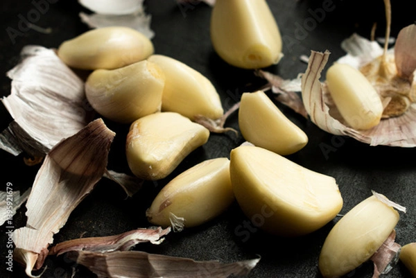 Obraz Close up of A rustic scene featuring garlic cloves and peelings scattered, great for illustrating cuisine, food preparation, cooking concepts, and rustic or organic kitchen themes.