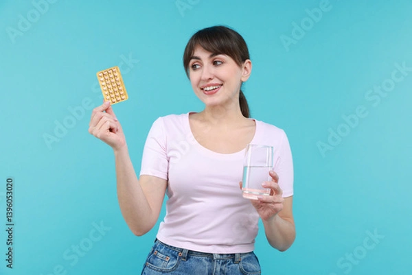 Obraz Smiling woman with contraceptive pills and glass of water on light blue background