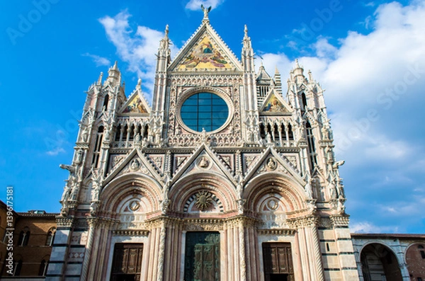 Fototapeta La facciata del duomo di Siena in una giornata estiva con il cielo azzurro e qualche nuvola
