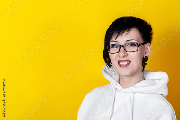 Obraz Gothic style charming brunette smiling woman in white jacket and glasses against yellow background